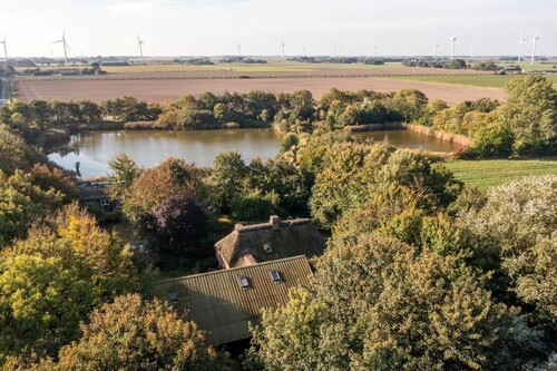 Denkmalgeschütztes Bauernhaus unter Reet mit Scheune auf einer Warft im Gotteskoog